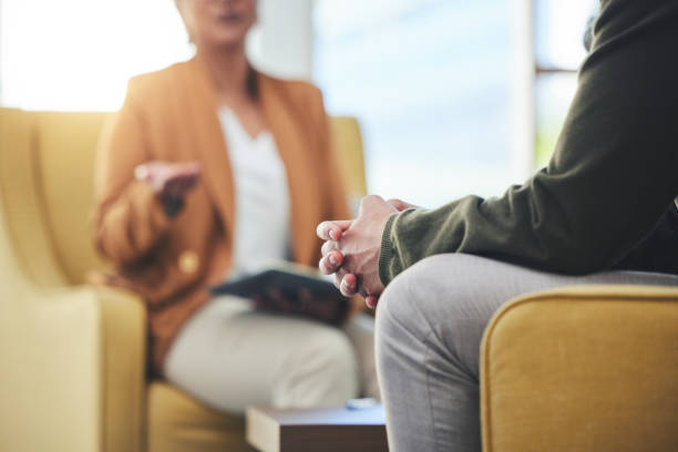 Mains jointes lors d'un échange confidentiel avec un psychologue, dans une ambiance calme et privée.